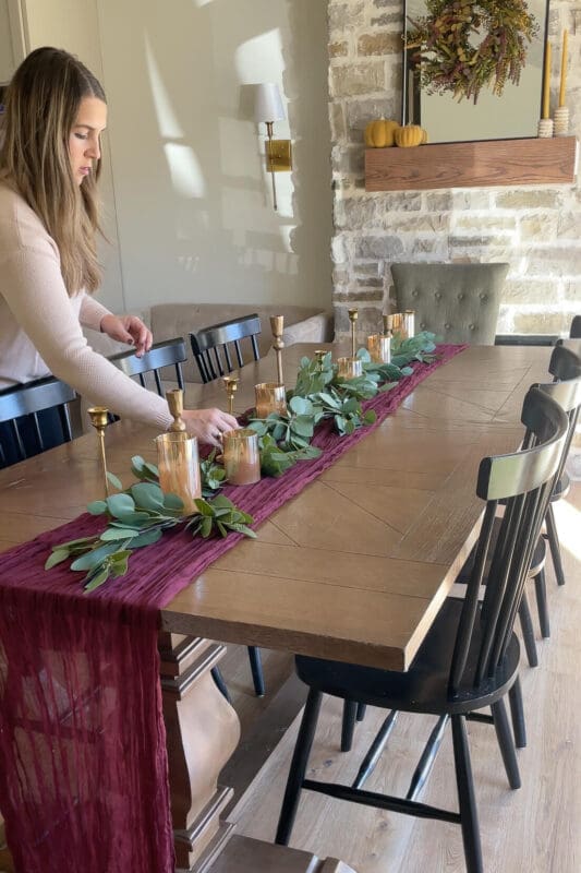 Adding brass candlesticks and gold glass pillar candles along the eucalyptus garland